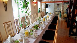 A long dining table set with white tablecloths, plates, glasses, and napkins. - City Gate Hotel (Vilnius)