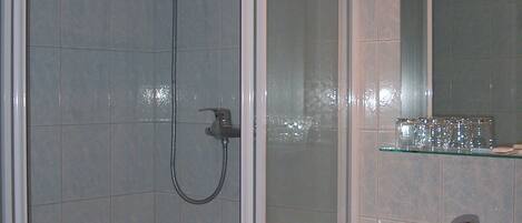A bathroom with a glass-enclosed shower, a sink, and a mirror above it.