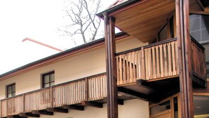 An outdoor seating area with wooden tables and chairs, a stone wall, and a wooden balcony. - City Gate Hotel (Vilnius)