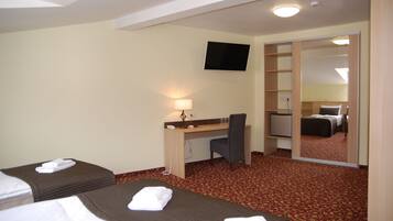 A hotel room with two beds, a desk, a chair, a TV, and a mirror.