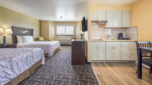 Une chambre d’hôtel avec deux lits, une kitchenette, un coin repas et une salle de bain.