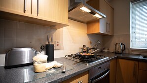 Una cocina moderna con armarios de madera, estufa a gas y un tostador.