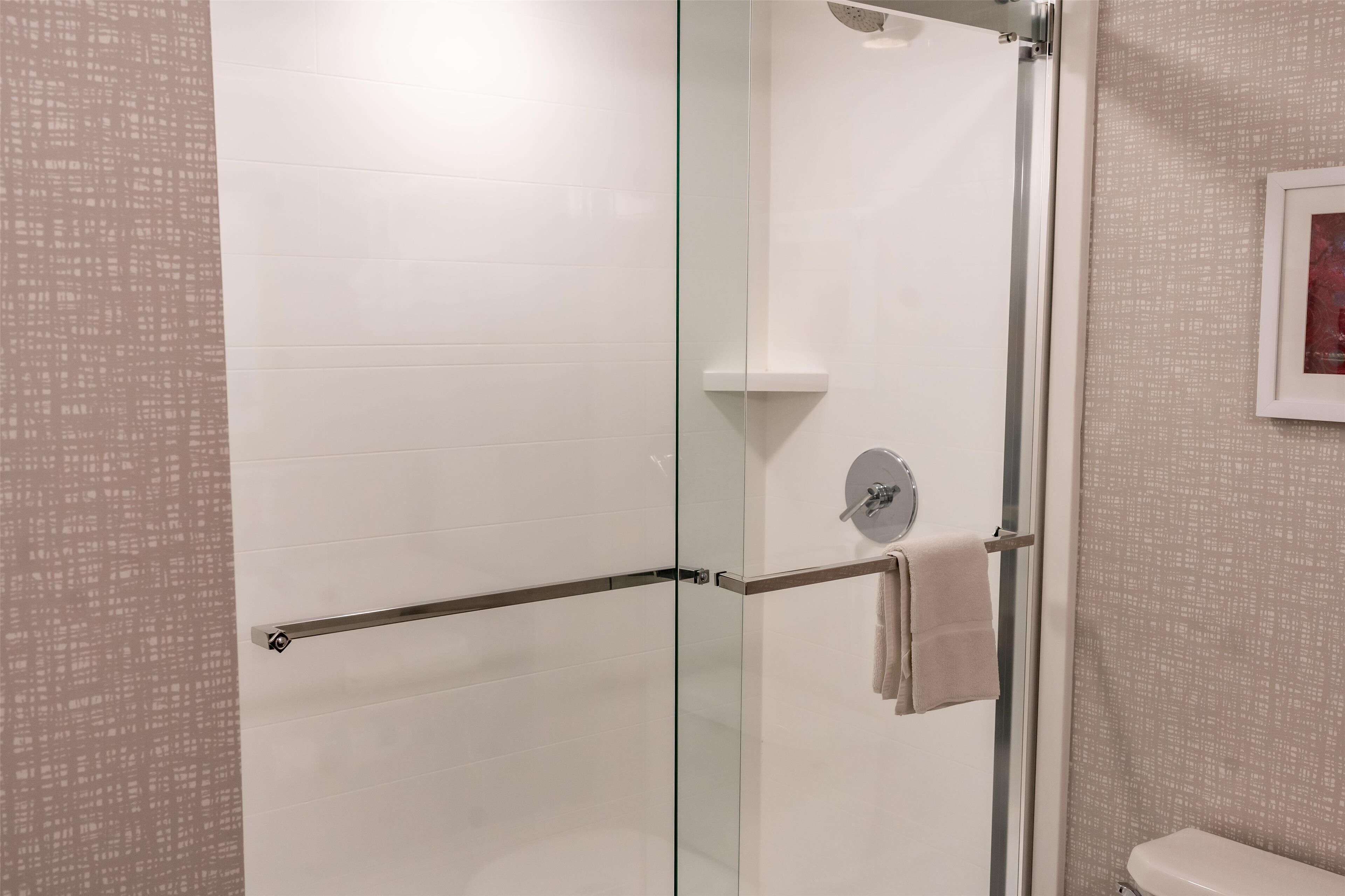 Un baño moderno con cabina de ducha de vidrio, un perchero para toallas y un inodoro.