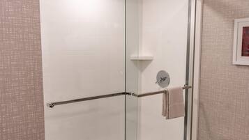 Un baño moderno con cabina de ducha de vidrio, un perchero para toallas y un inodoro.