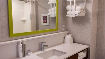 A bathroom with a large mirror, a sink, and towel storage.