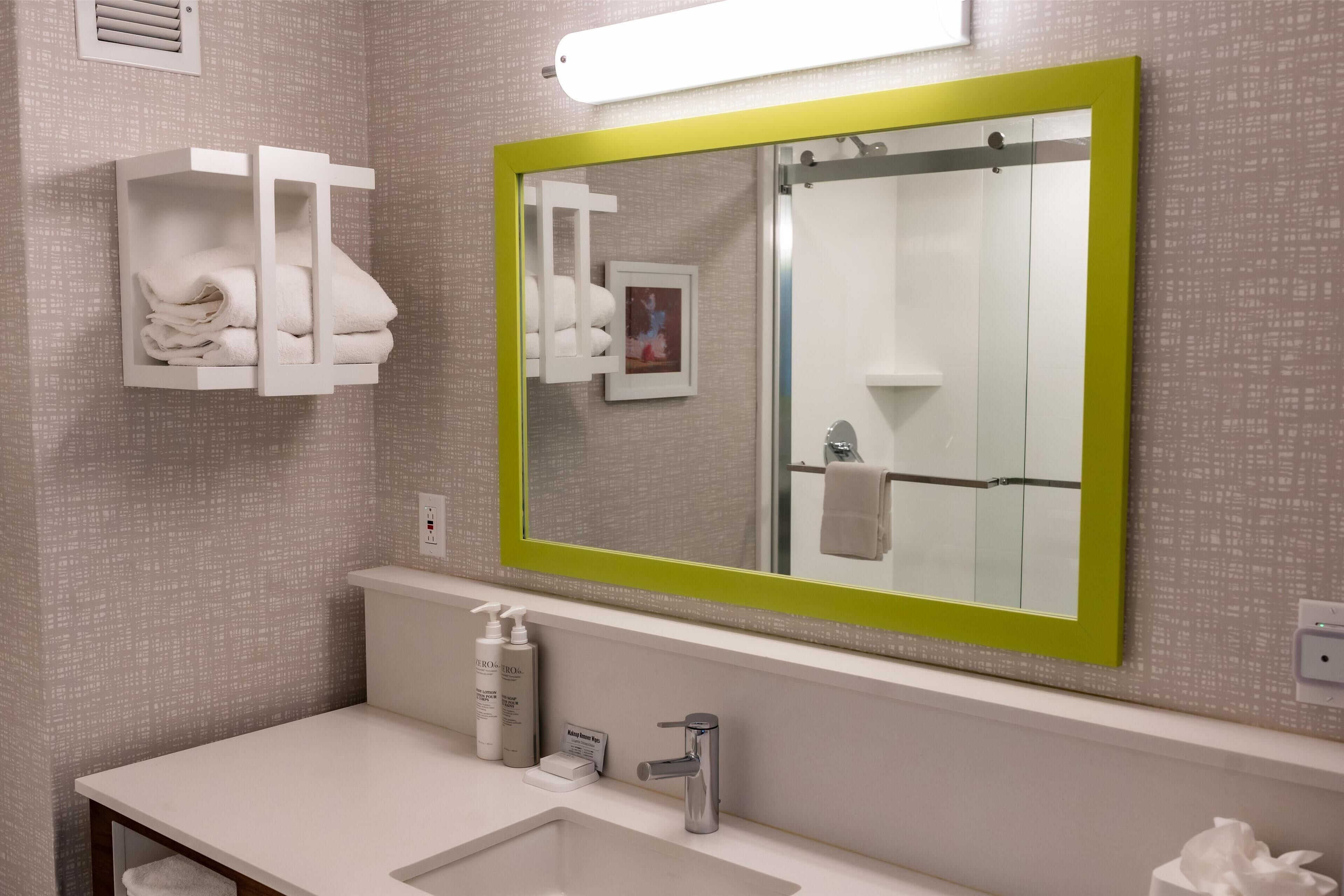 A modern bathroom with a large mirror, a sink, and a towel rack.