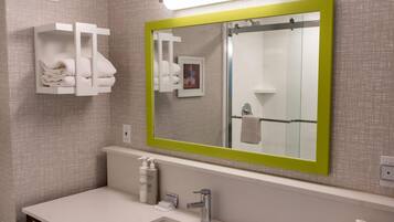 A modern bathroom with a large mirror, a sink, and a towel rack.