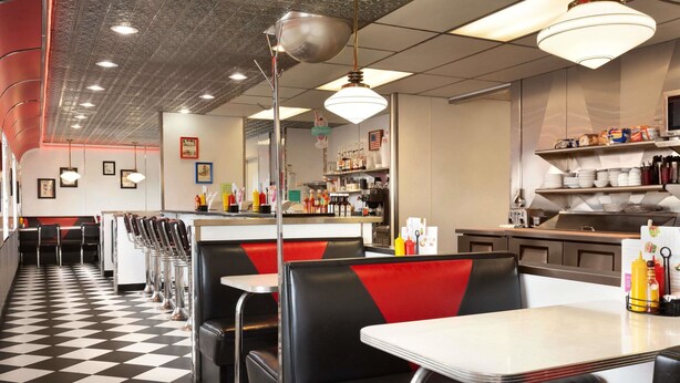 A diner with booths and tables, checkered floor, and a kitchen area visible in the background. - Travelodge by Wyndham Milford (Milford)