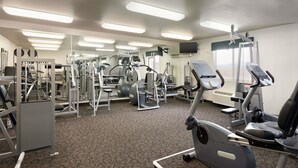 A gym with various exercise machines, a television, and a window with blinds. - Travelodge by Wyndham Milford (Milford)