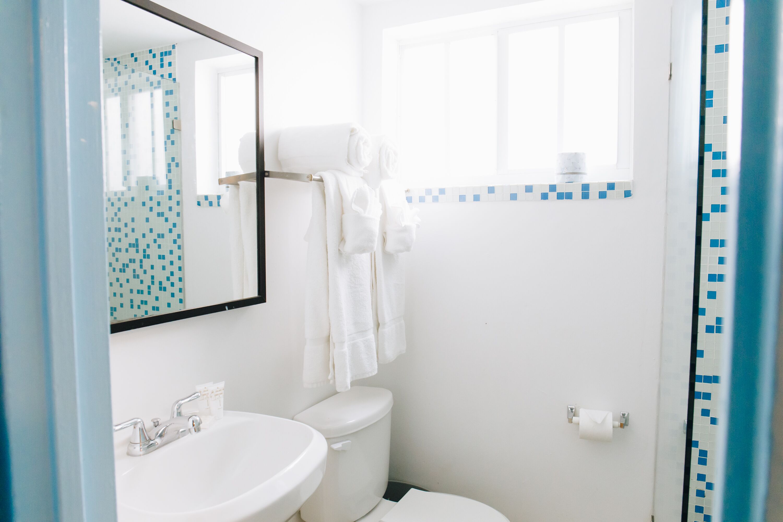 Un baño con lavamanos blanco, inodoro y ventana sobre el inodoro.