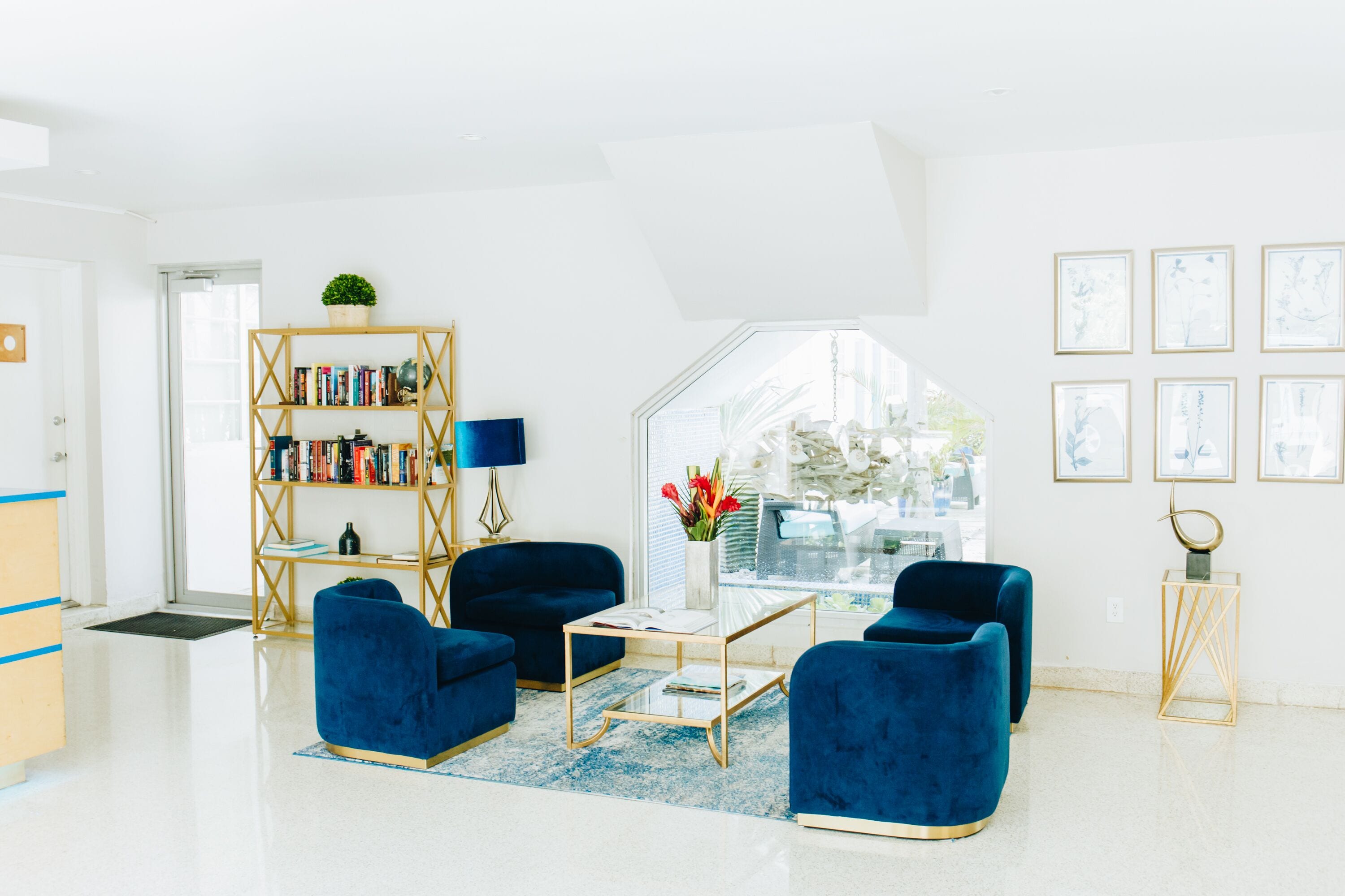 A modern living room with a blue sofa set, a glass coffee table, and a bookshelf.