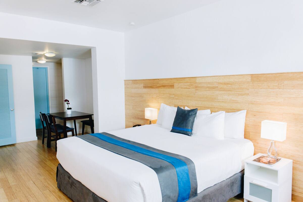 A hotel room with a large bed, a desk with chairs, and a wooden headboard.
