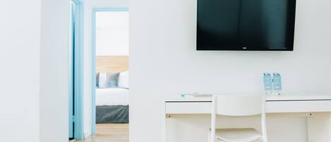 Una habitación moderna con un escritorio blanco, una silla blanca y un televisor de pantalla plana montado en la pared.