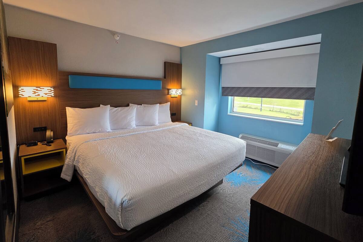 A hotel room with a large bed, bedside tables, a desk, and a window with a view.
