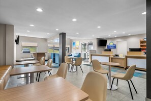 A hotel lobby with seating areas, a reception desk, and a large window offering a view of the outdoors. - Days Inn & Suites by Wyndham Brandon Amphitheater (Brandon)