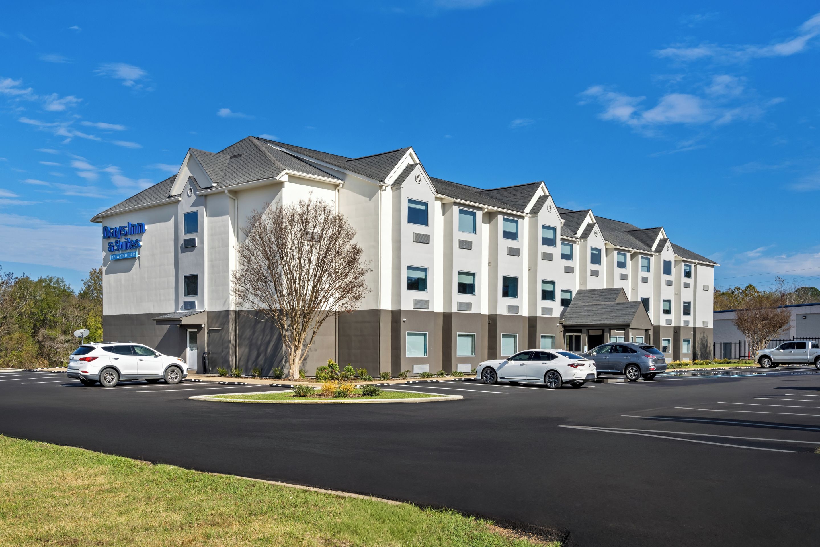 A multi-story hotel with a parking lot in front.