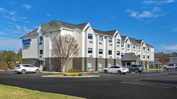 A multi-story hotel with a parking lot in front.