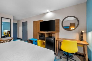 A hotel room with a bed, a desk with a chair, a television, a microwave, and a refrigerator. - Days Inn & Suites by Wyndham Brandon Amphitheater (Brandon)