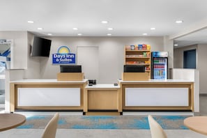 A reception area with a sign for Days Inn & Suites, a self-service kiosk, a snack shelf, and a refrigerator with beverages. - Days Inn & Suites by Wyndham Brandon Amphitheater (Brandon)