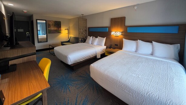 Ein Hotelzimmer mit zwei Betten, einem Schreibtisch, einem Stuhl und einem Fernseher.
