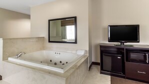 Un baño moderno con una bañera grande, un tocador con televisor de pantalla plana y un espejo sobre el tocador.