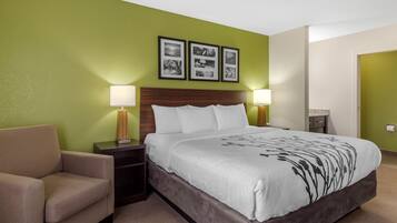 A hotel room with a bed, a chair, two bedside tables with lamps, and three framed pictures on the wall.