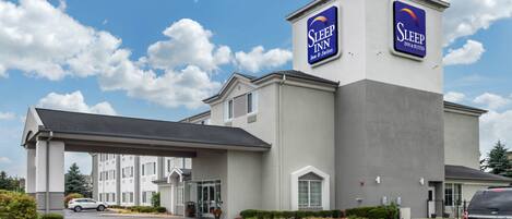 A Sleep Inn hotel with a modern design, featuring a prominent signage, a covered entrance, and a parking lot.