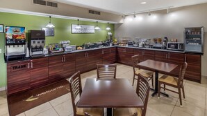 Una cocina moderna con una pared verde de acento, una cafetera, un microondas y un cubo de basura.