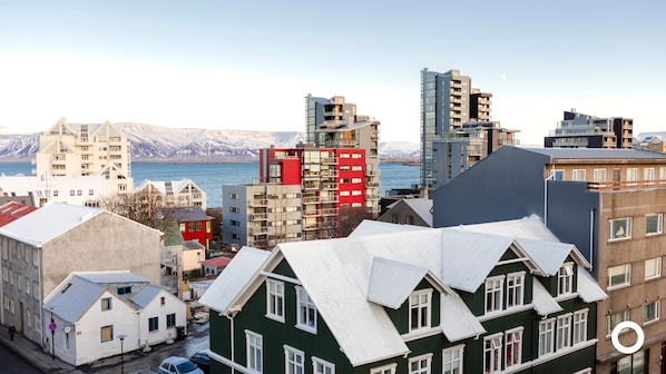 A coastal cityscape with modern and traditional buildings, a view of the sea, and mountains in the background. - Center Hotels Klöpp (Reykjavik)