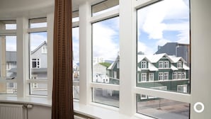 A room with large windows offering views of traditional houses and a clear sky. - Center Hotels Klöpp (Reykjavik)