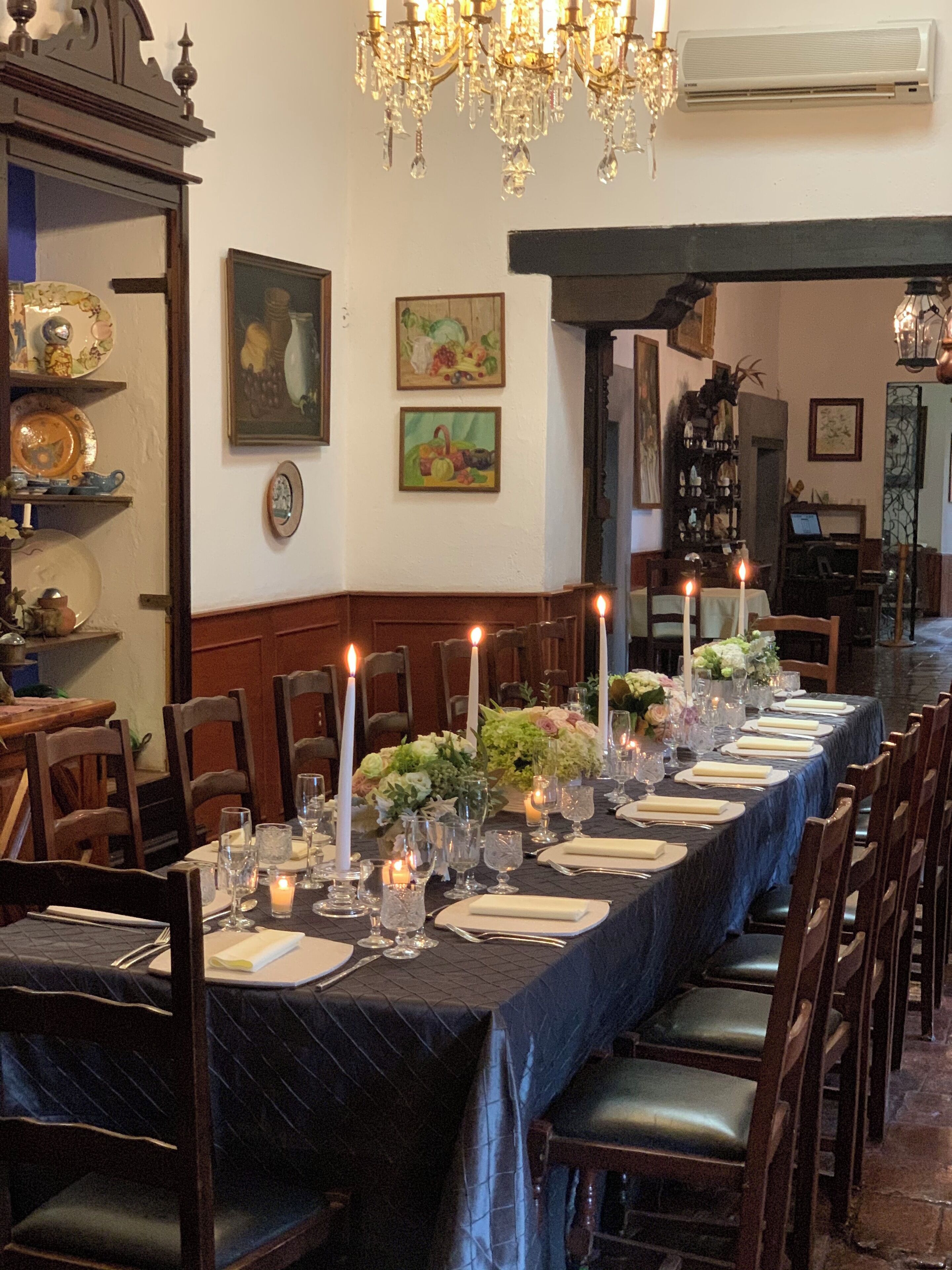 A long dining table set for a formal meal with candles, glassware, and floral centerpieces.