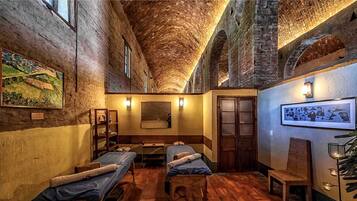 Experience the charm of this historic room with exposed brick walls and a vaulted ceiling, featuring two single beds and a cozy seating area.