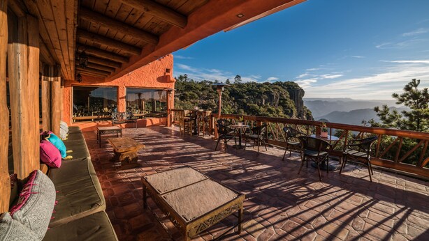 Una terrazza esterna con mobili in legno, pavimento in pietra e vista sulle montagne.