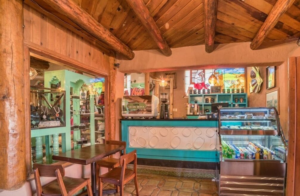 Ambiente rustico con travi in legno, angolo bar con macchina da caffè e vetrina refrigerata.