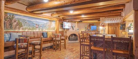 A cozy interior with a stone-tiled floor, wooden furniture, a fireplace, and a mural on the wall.