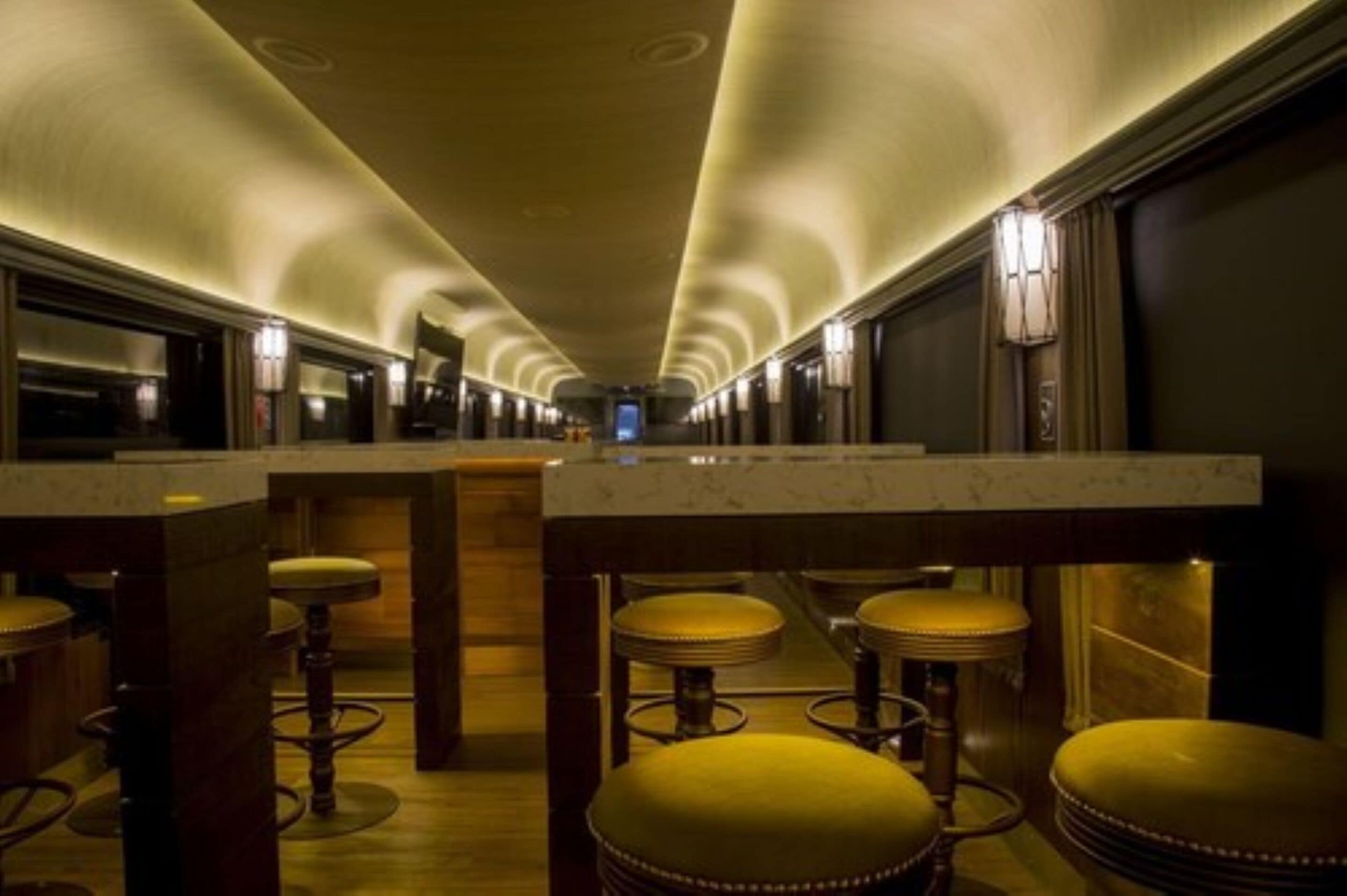 A long, narrow hallway with a series of bar stools and a marble counter.