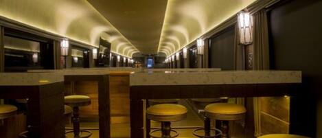 A long, narrow hallway with a series of bar stools and a marble counter.