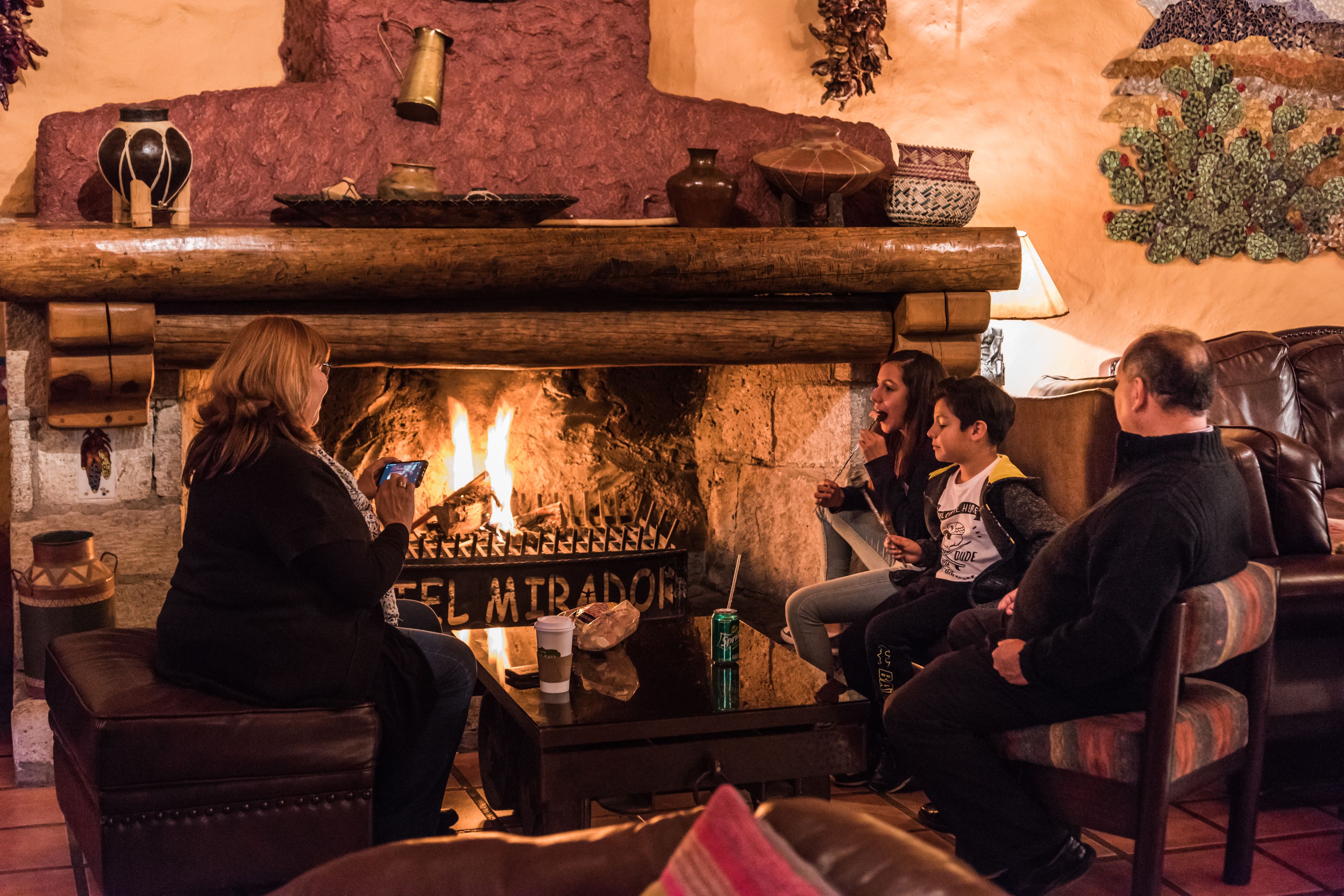 Un interior acogedor con chimenea, asientos de cuero y una pared de piedra.