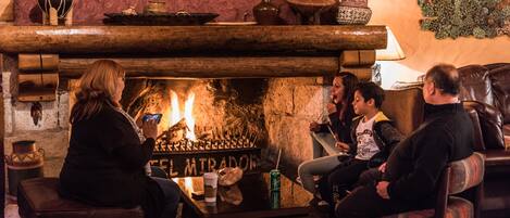 Un interior acogedor con chimenea, asientos de cuero y una pared de piedra.