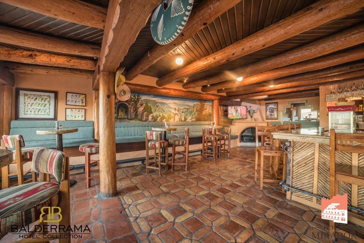 Un interior rústico con vigas de madera, suelo de piedra y una zona de bar.