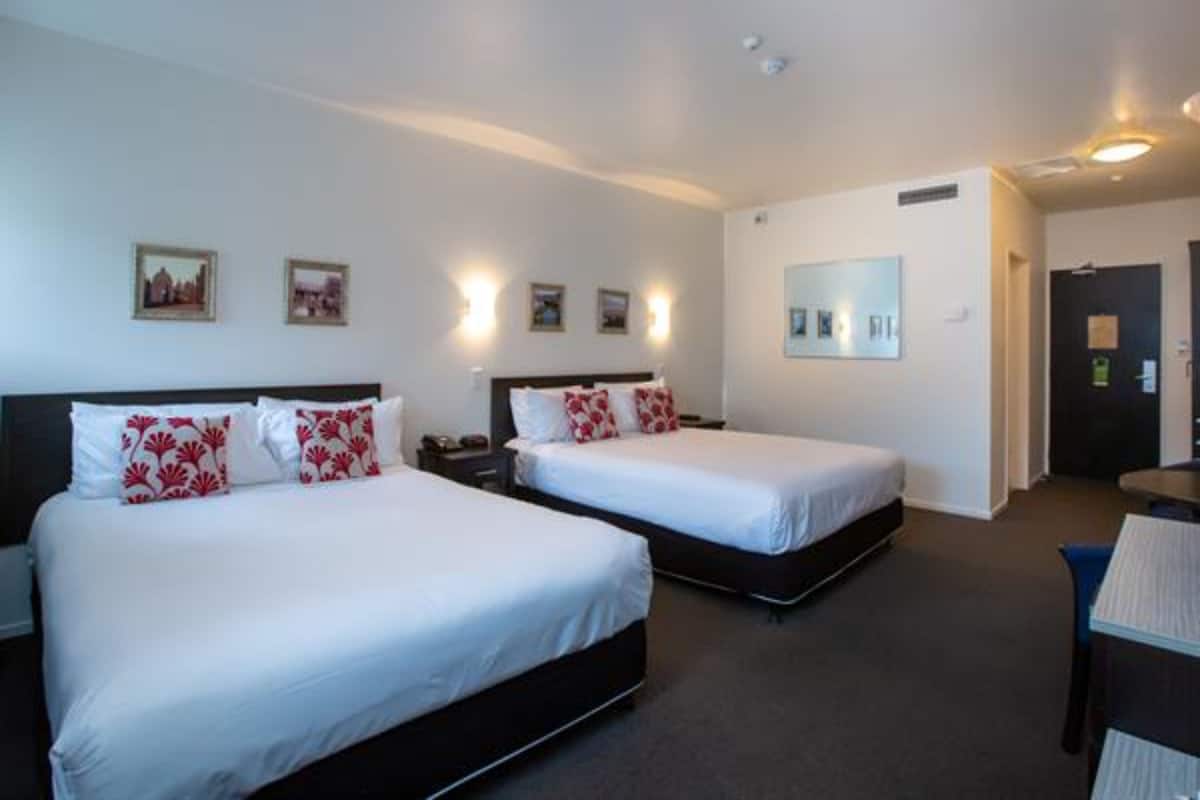 Ein Hotelzimmer mit zwei Betten, einem Schreibtisch und einem Stuhl.