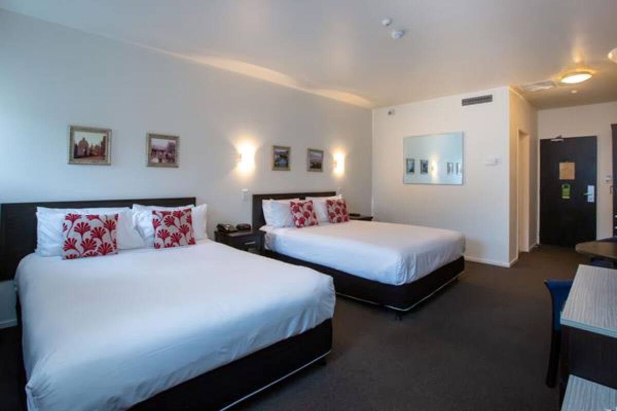 Ein Hotelzimmer mit zwei Betten, einem Schreibtisch und einem Stuhl.