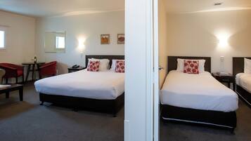 A hotel room with two beds, a desk, a chair, and a small table.