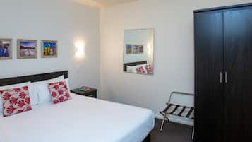 A hotel room with a bed, a nightstand, a wardrobe, and wall-mounted artwork.