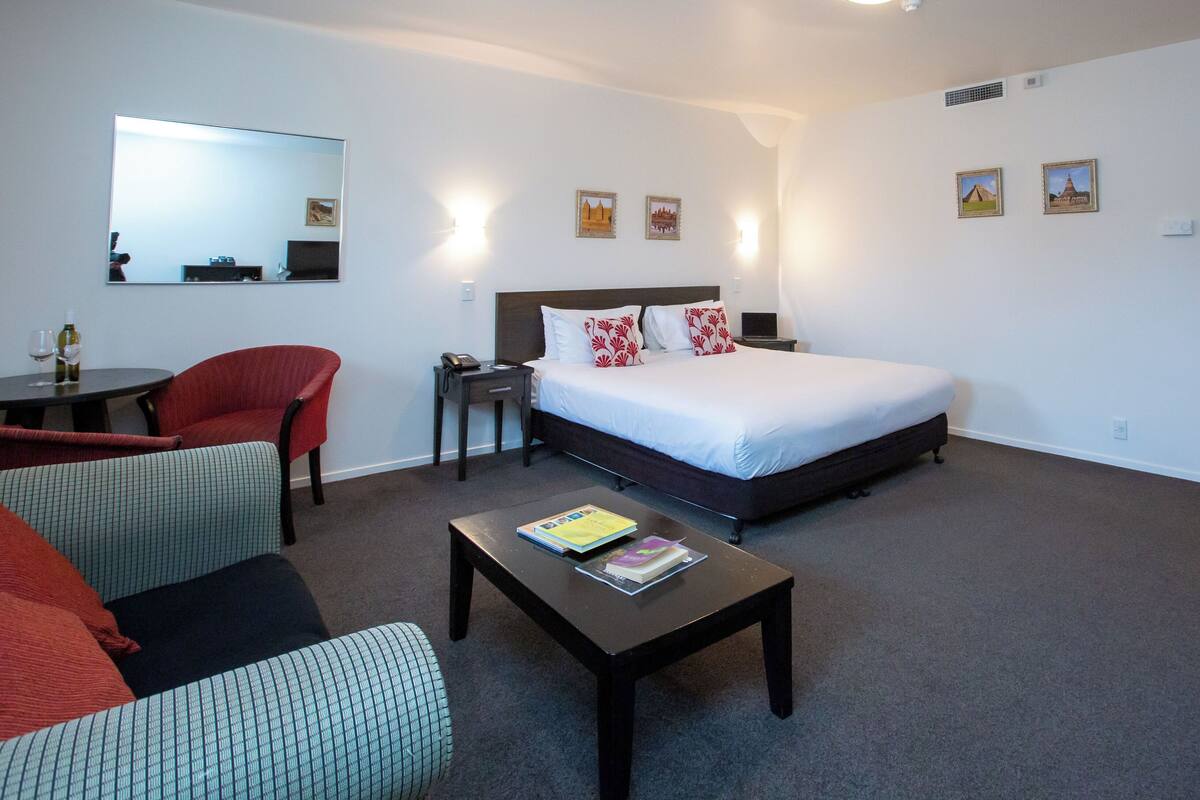 Ein Hotelzimmer mit einem Bett, einem Schreibtisch, einem Sessel, einem kleinen Tisch und einer Couch.