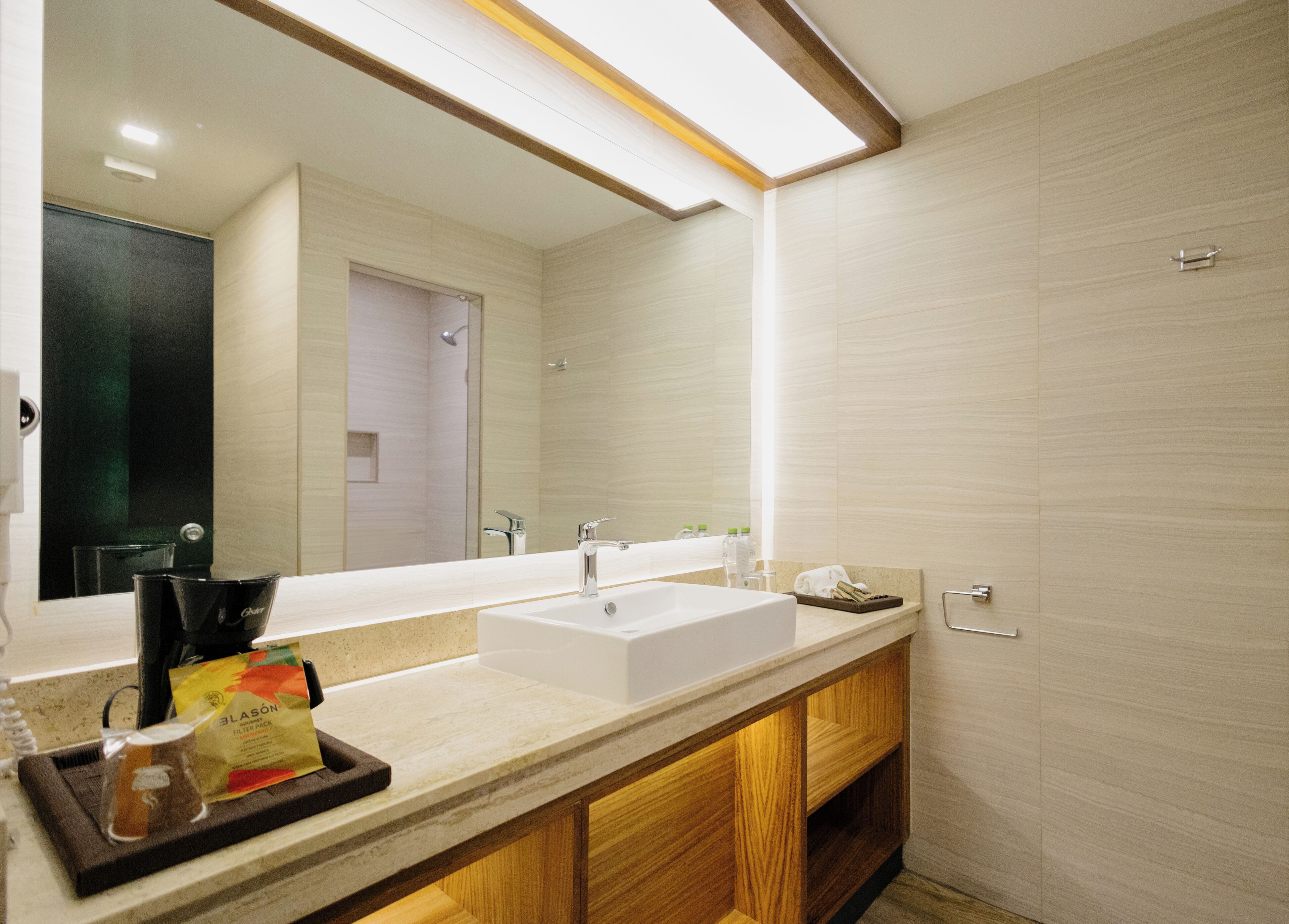 A modern bathroom with a large mirror, a white sink, and wooden cabinets.