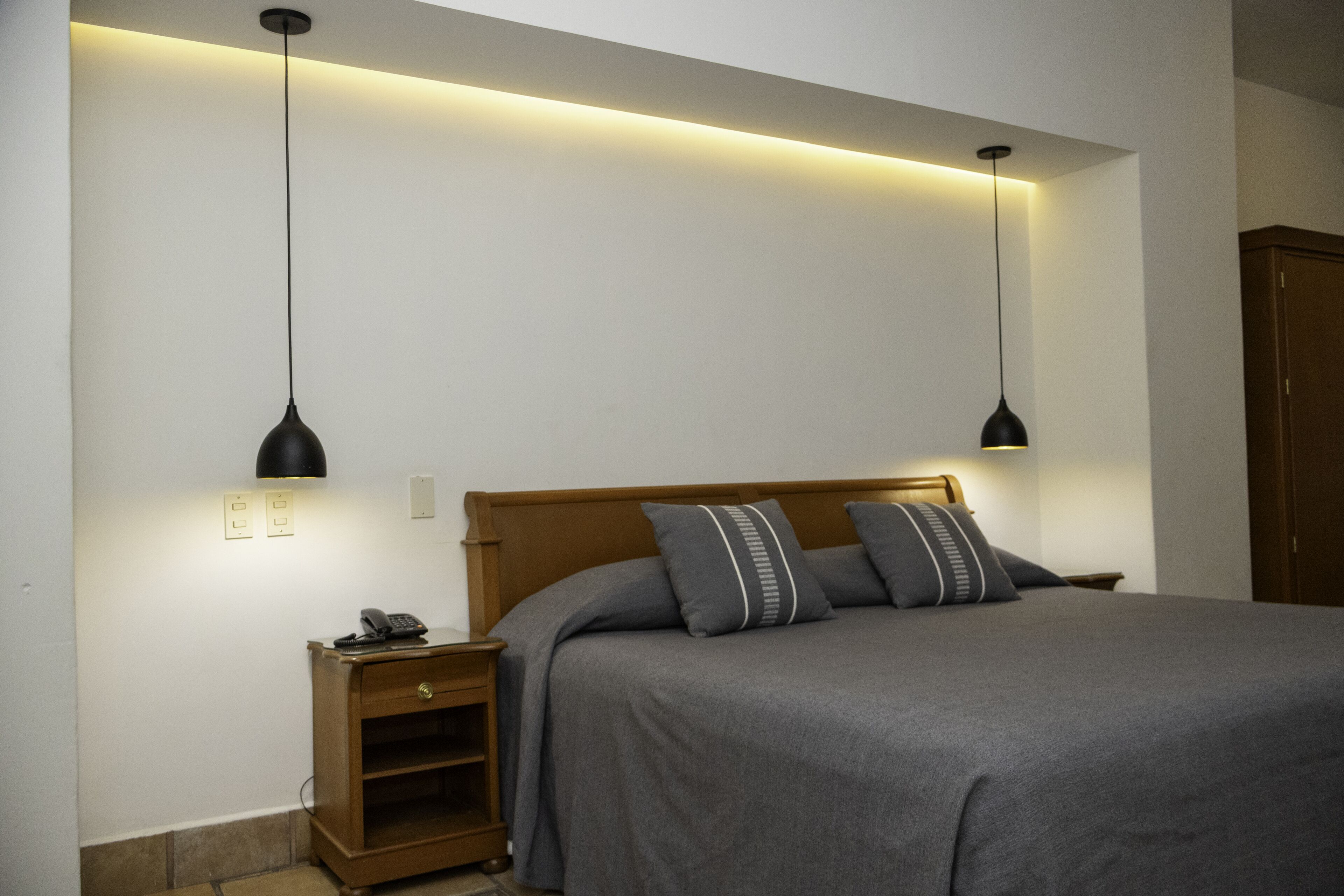 A bedroom with a bed, bedside tables, and pendant lights.