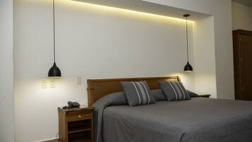 A bedroom with a bed, bedside tables, and pendant lights.