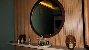 A mirror with a wooden frame, a shelf with candles, and a small plant.