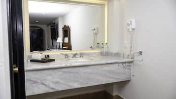 A bathroom with a marble sink, a large mirror, and a hairdryer mounted on the wall.